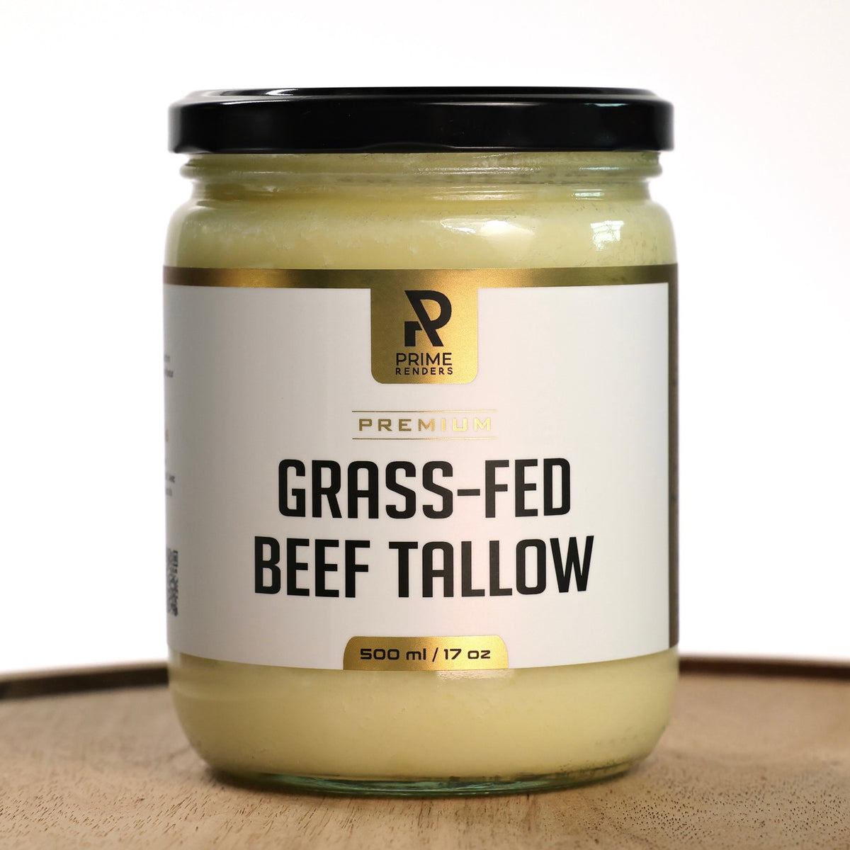 Jar of Prime Renders grass-fed beef tallow with a visible label on a wooden surface.