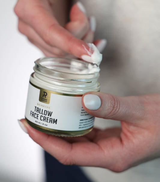 woman holding a jar of prime renders tallow face cream and scooping it with her finger