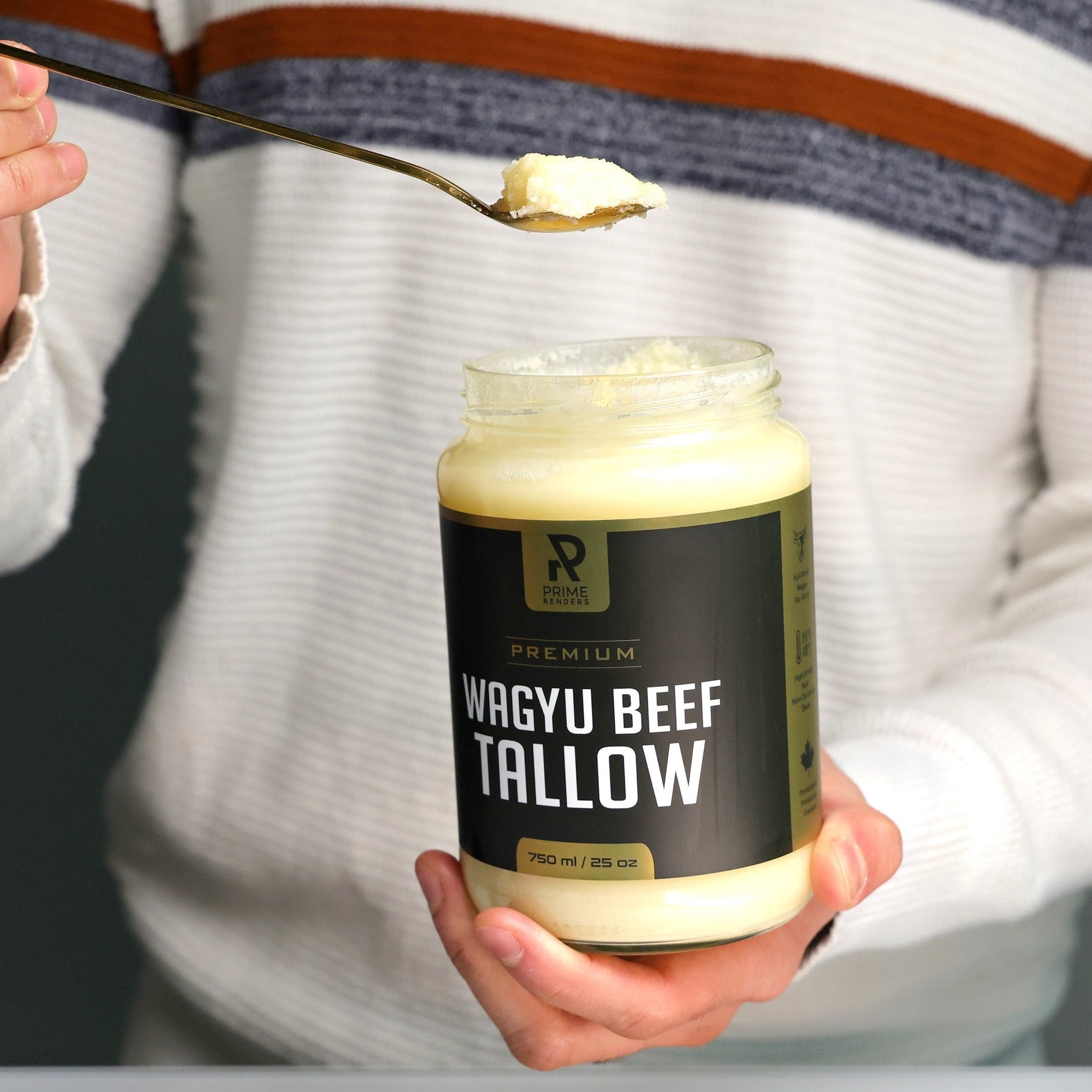 Person holding a jar of Wagyu Beef Tallow with a spoonful above it on a cutting board.
